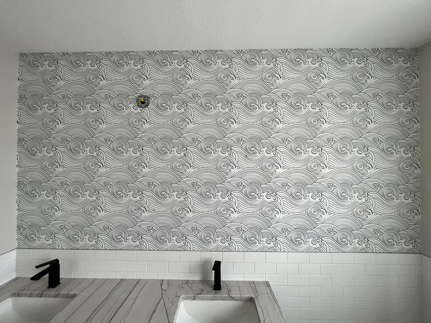 Wave pattern wallpaper behind a bathroom vanity