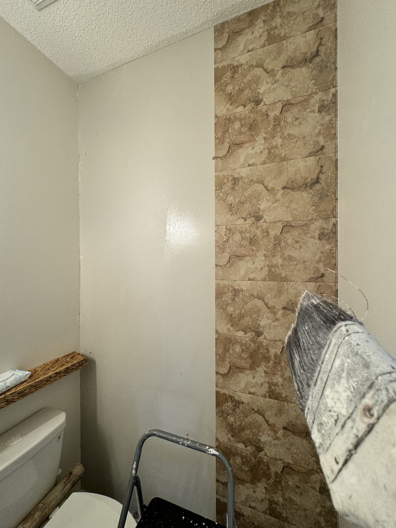 Stone-look wallpaper being smoothed onto a bathroom wall